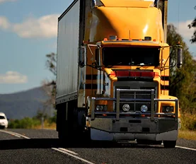 Yellow semi-trailer truck on a rural road